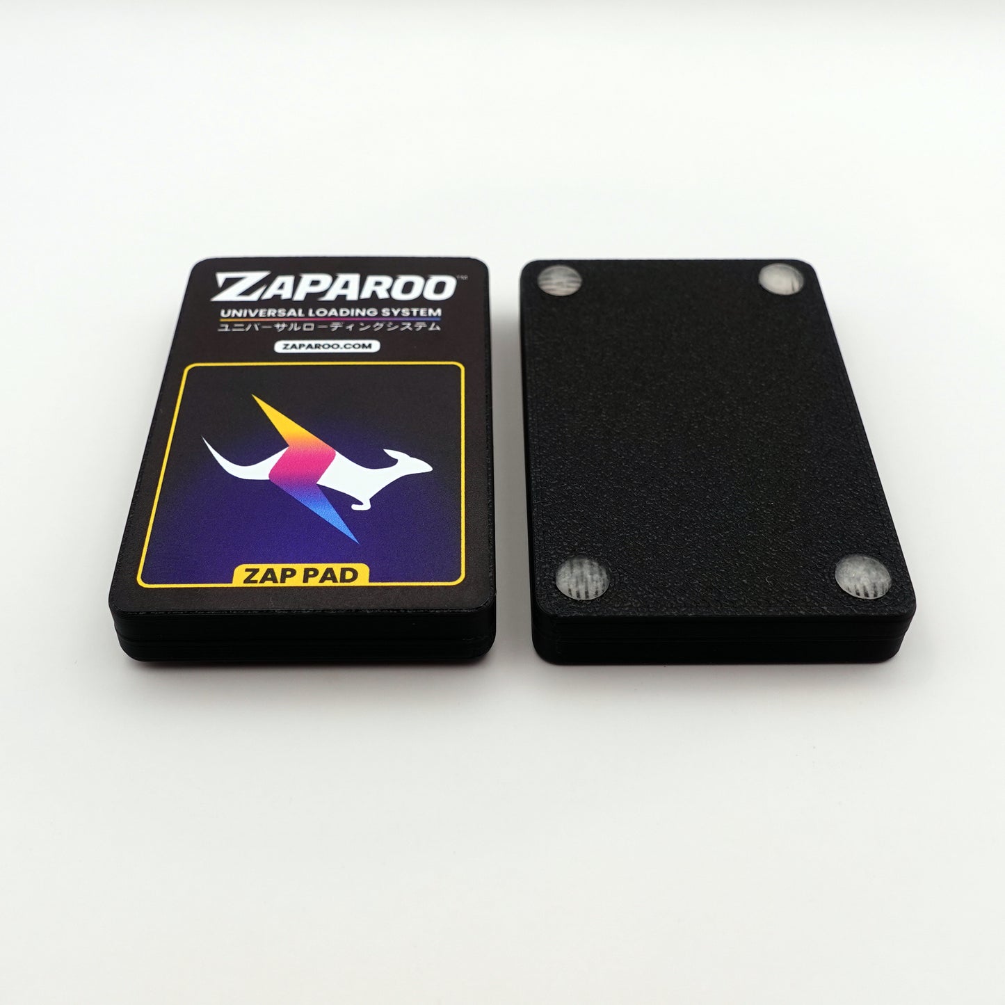 A front shot of two Black Zap Pads, one face up showing the label and one face down showing the rubber feet.